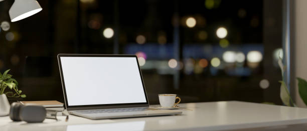 istock A laptop computer and accessories on a table against the window with a night city view. 2159452076