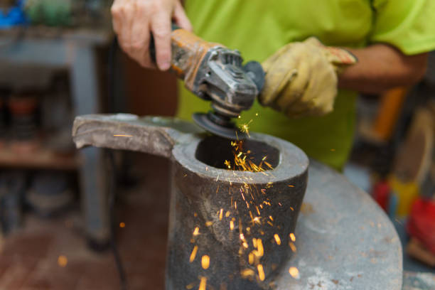 A man operates a grinder to slice through metal. Sparks burst from the grinder, scattering wildly and creating a hazardous and electrifying scene