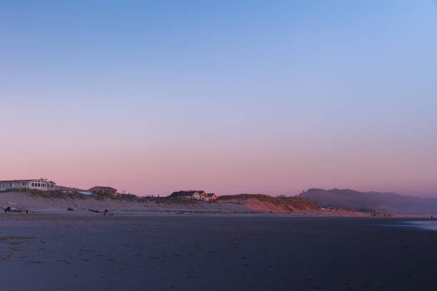 Beach, Ocean Surf, Luxury Waterfront Houses,Turquoise Water, Dark Blue Sky and Tourists Walking Along the Water Edge in Background, Wells, Maine, USA.
