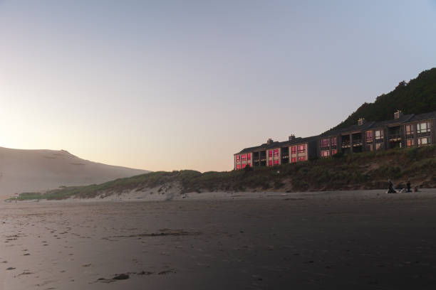 A peaceful and calming scene as the sun sets over the Pacific Ocean on the Oregon Coast in summer time. Vacation, road trip and landscape concepts. Image shows rows of beach front properties from the beach point of view standing on the sand.