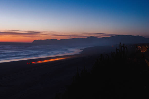 Long exposure with camera on a tripod of the Oregon coast at sunset. Images feature car lights as light trails from the long exposure. Shot with copy space, travel, tourism, and road trip concepts.