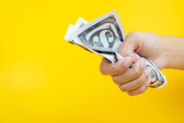 istock Female hands holding banknotes on a yellow background. 2159456839