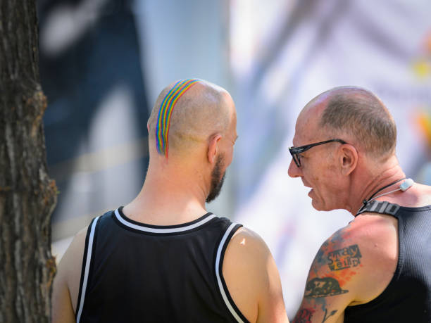 Vienna, Austria - June 08, 2024: People at Vienna Pride in summer on Wiener Ringstrasse, head of a bald man painted with rainbow colors