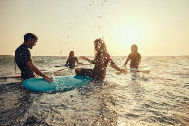 istock Cheerful surfers having fun while splashing in sea at sunrise. 2159462629