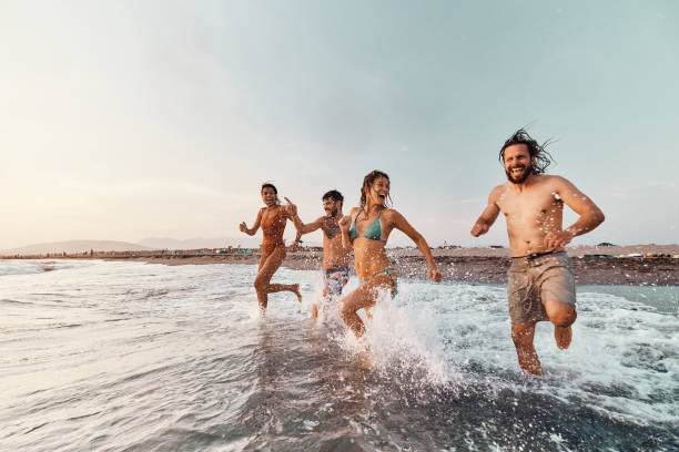 istock Cheerful friends running through sea in summer day. 2159462646