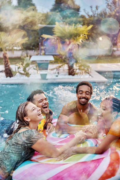 istock Young cheerful friends talking on inflatable raft at the pool. 2159463699