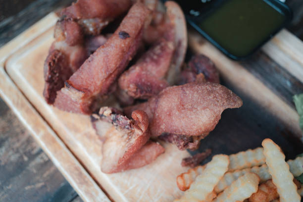 Crispy deep fried pork leg with potato french fries on wood tray