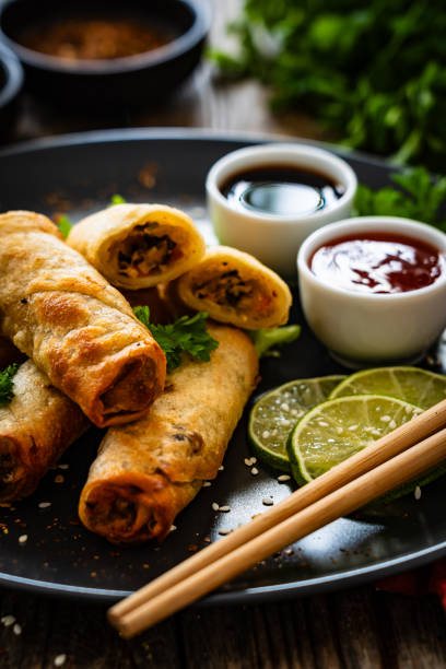 istock Spring rolls filled with meat and vegetables served with soy sauce on wooden table 2159469658