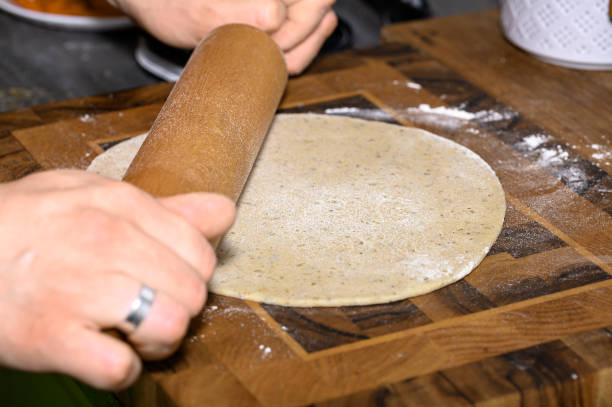 Roll out the raw dough on a wooden table with a wooden rolling pin