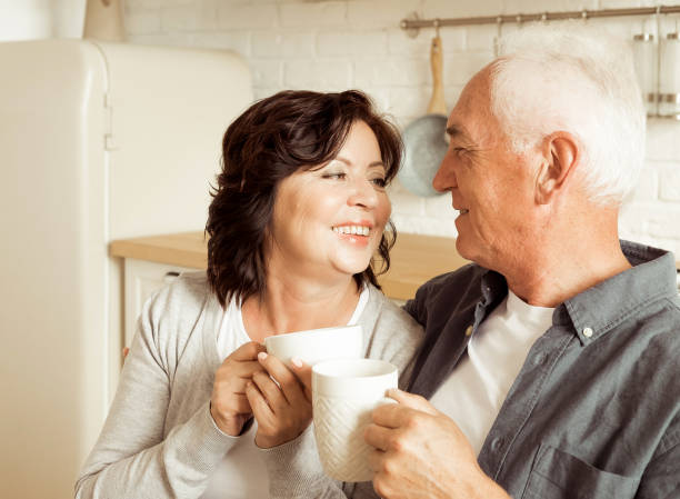 istock Happy elderly couple drinking coffee in the kitchen while sitting at the table. 2159470821