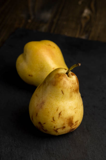 ripe pear on a black slate, ripe green and yellow pear on a board