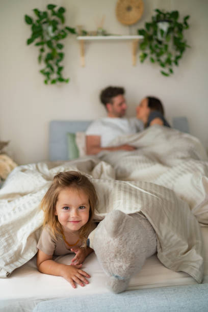 istock Girl with a teddy bear is lying on her parents' bed 2159479319