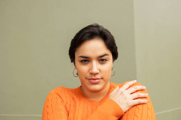 istock Young woman hugging self against beige wall 2159486055