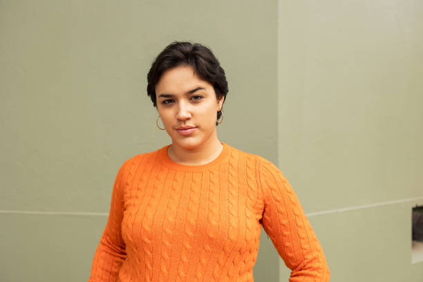 istock Confident young woman standing against beige wall 2159487530