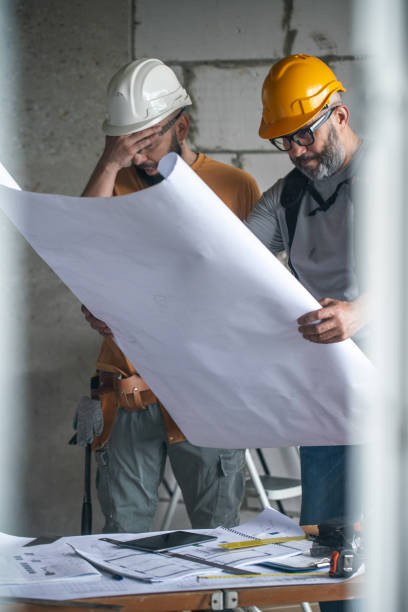 istock Two construction workers check blueprints at a construction site, one of them covers his face with his hand 2159488872