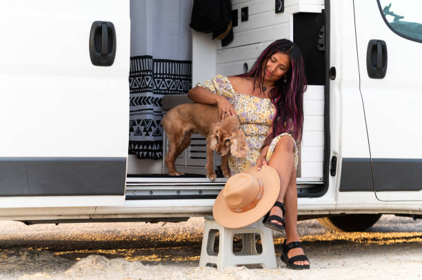 istock Young woman petting dog while relaxing in camper van at beach 2159490162