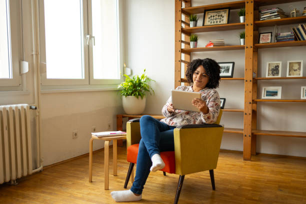 istock Focused woman using digital tablet on armchair at home office 2159490208