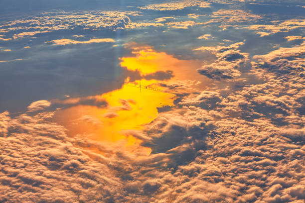 Sky is filled with clouds and the sun is shining through them. The clouds are white and fluffy, and the sun is casting a warm glow on the scene. Flight over the bay