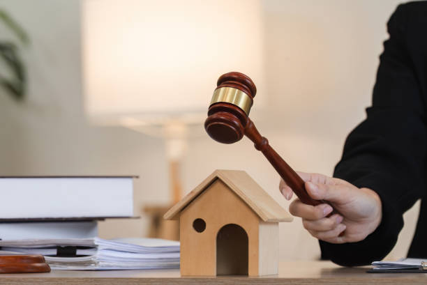 Real Estate Law Concept with Judge's Gavel and Model House on Desk Judge's gavel striking a model house, symbolizing real estate laws and property regulations. Legal documents and books in the background. civil rights act stock pictures, royalty-free photos & images