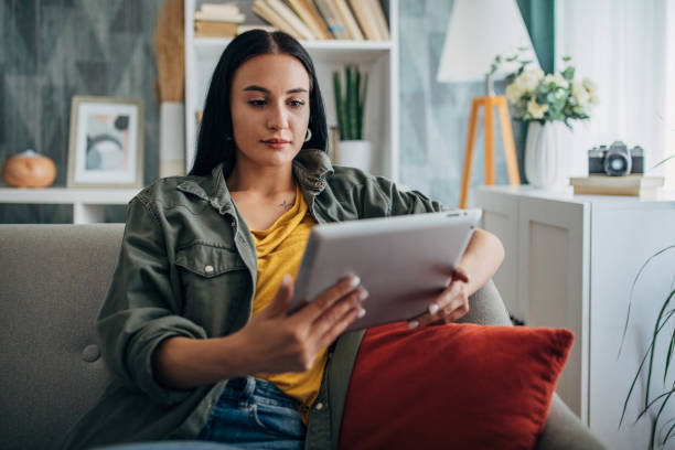 istock Woman reading on tablet in cozy living room setting 2159492959