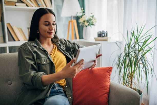 istock Smiling woman using tablet on couch in bright cozy home. 2159493091