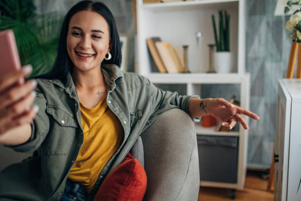 istock Woman laughing while taking a selfie on a couch. 2159493726