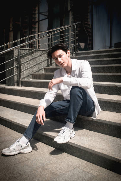 istock Handsome young man, student sits on steps in city 2159495045