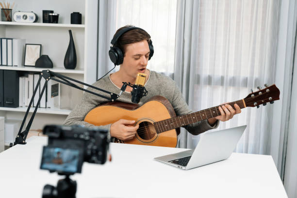 istock Smart singer recording by camera, playing guitar along singing. Pecuniary. 2159500070