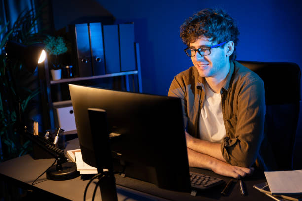 istock Smiling businessman concentrating on pc on project at neon light office. Gusher. 2159500872