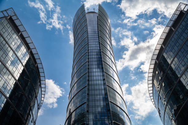 The mesmerizing symmetry of three glass skyscrapers reaching towards the sky. The reflective facades mirror the clouds and blue sky, creating a sense of infinity as the buildings converge in the upper frame.