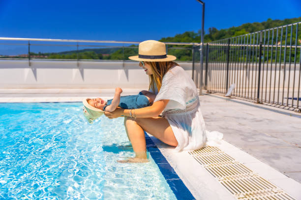 istock Mother playing with a baby sitting on a pool 2159504428