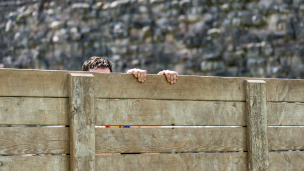 Two hands holding on to a wall while an athlete tries to overcome the wall in an obstacle course