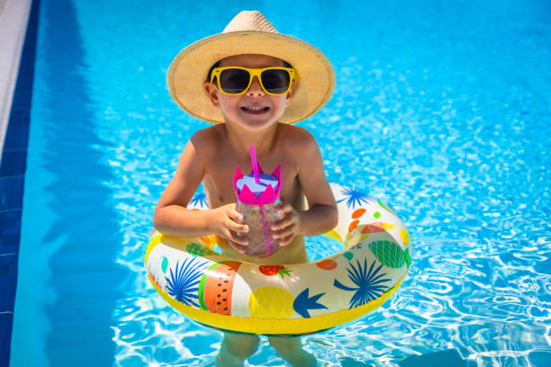 istock Happy boy with sun hat drinking water in a pool 2159505222