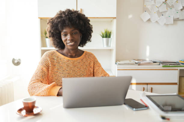 istock Smiling woman using laptop at table in home office 2159506721