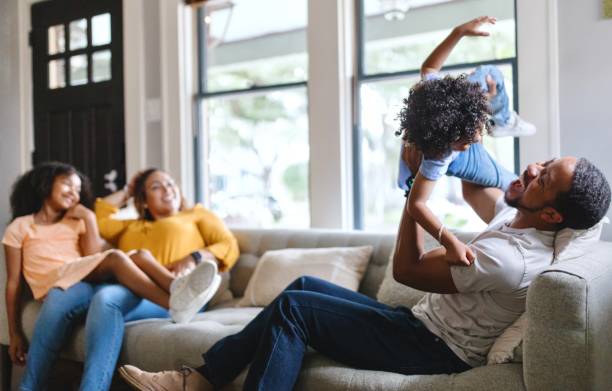 Joyful parents sitting on the sofa with their cute kids