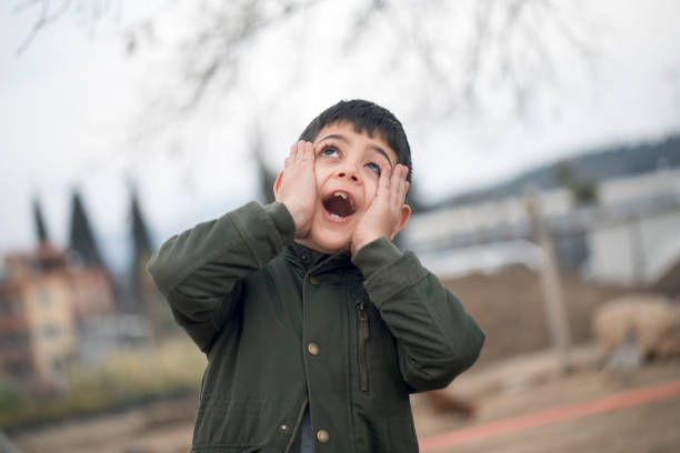 Portrait of cute little Asian boy at his desk, looking to his right with surprise expression over white background.