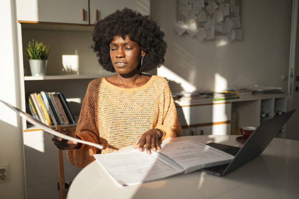 istock Woman reading document carefully while working with laptop in home office 2159513601