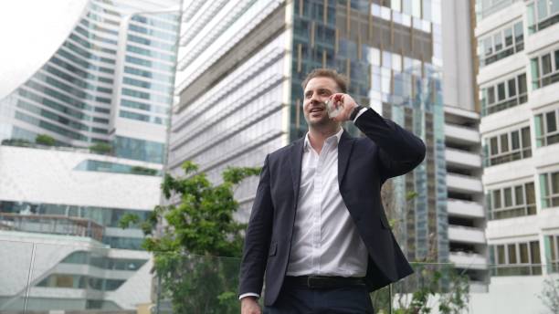 istock Businessman talking to team by using phone while standing at skyscraper. Urbane. 2159513656
