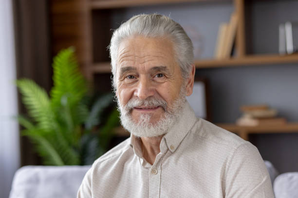istock Smiling elderly man with grey hair and beard sitting in cozy home environment 2159513905