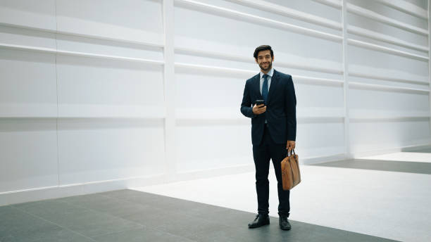 istock Skilled manager looking at phone while standing at white background. Exultant. 2159515082