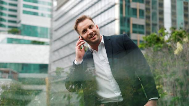 istock Businessman standing at rooftop while talking with team by using phone. Urbane 2159515436