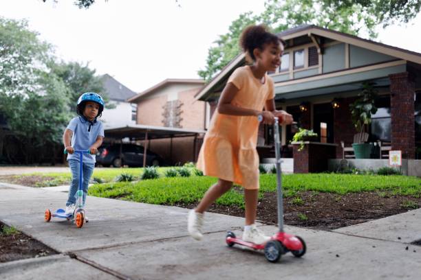 istock Siblings riding scooters on a sidewalk 2159517605