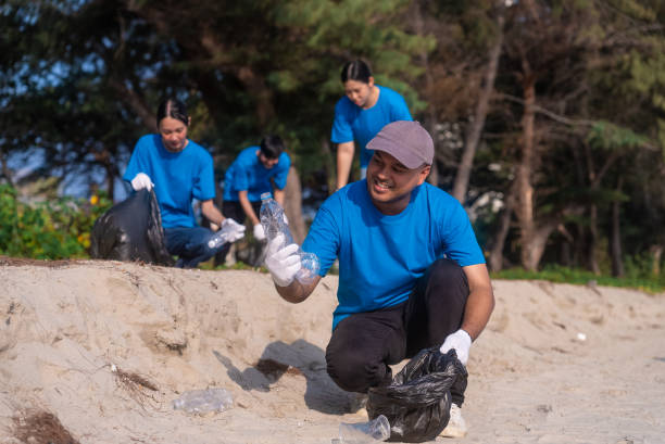 istock Plastic pollution and environmental problem concept. Happy asian diverse group of volunteers with garbage bags wearing blue t-shirt and cleaning plastic on the beach. Volunteers collecting trash. 2159517872