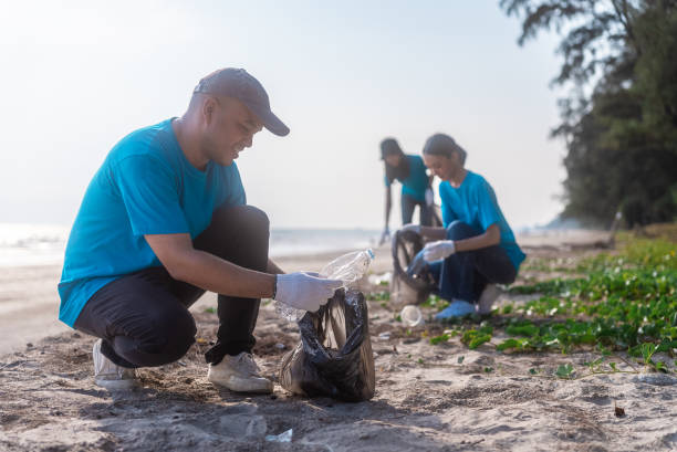 istock Plastic pollution and environmental problem concept. Happy asian diverse group of volunteers with garbage bags wearing blue t-shirt and cleaning plastic on the beach. Volunteers collecting trash. 2159517895