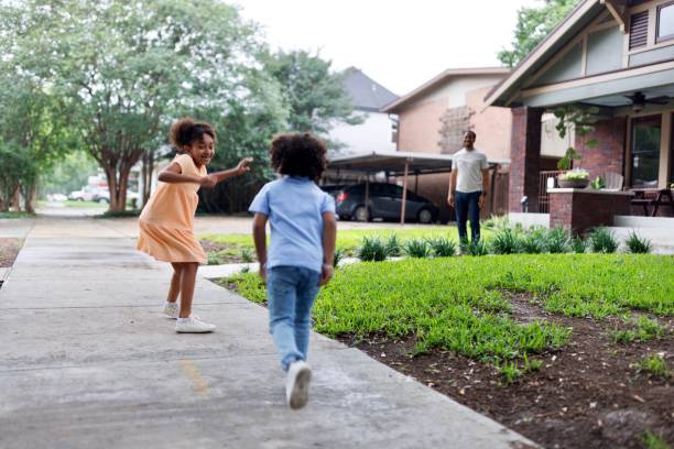 istock Siblings playing tag game in front of their house 2159518174