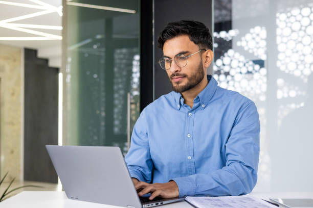 istock Focused young professional working on a laptop in a modern office 2159518700