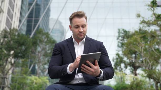 Smart businessman sitting while writing on tablet and planning strategy. Urbane