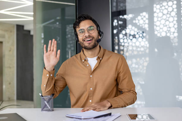istock Happy man waving during a video chat call in a modern office 2159520203