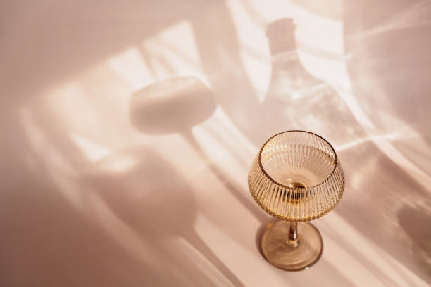 istock Two glasses with white wine placed on light beige background with shadows 2159521966
