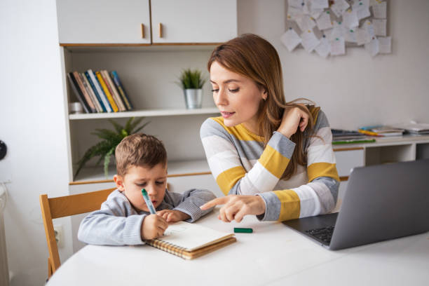 istock Mother with laptop helping son with homework at desk 2159522418